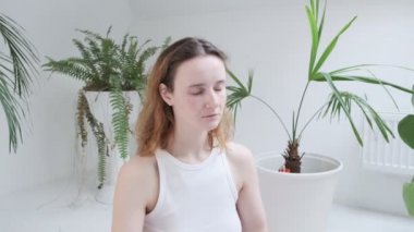 Spor kıyafetleri giyen bir kız Lotus pozisyonunda oturur. Gözleri kapalı, meditasyondan zevk alır.