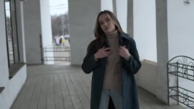 asian thoughtful girl in blue coat posing on veranda with white stone columns