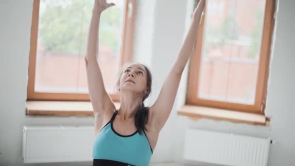Молодая спортивная брюнетка в спортивной одежде делает упражнения в светлой комнате дома — стоковое видео