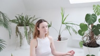 Spor kıyafetleri giyen bir kız Lotus pozisyonunda oturur. Gözleri kapalı, meditasyondan zevk alır.
