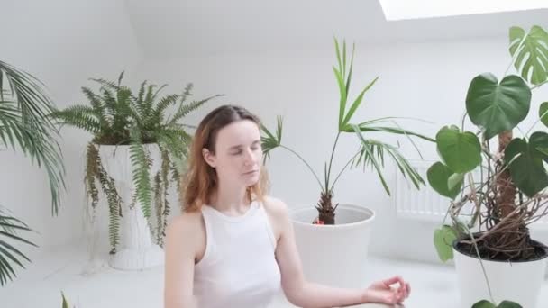 Flicka bär sportkläder sitter i lotus pose med slutna ögon njuter av meditation — Stockvideo