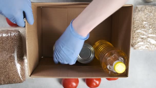 Colocando alimentos de supermercado em caixa de doação de papelão: legumes, óleo, cereais, latas de lata — Vídeo de Stock