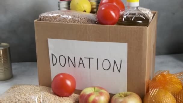 Pudełko darowizn na stole wypełnione żywnością spożywczą: warzywa, olej, zboża, owoce — Wideo stockowe