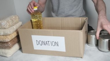 Gönüllü bağış kutusuna yiyecek koyar. Coronavirus yardım fonu, hayır kurumu, teslimat