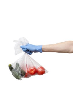 Beyaz arka planda mavi eldivenler giyerek elde tutulan sebzeler.