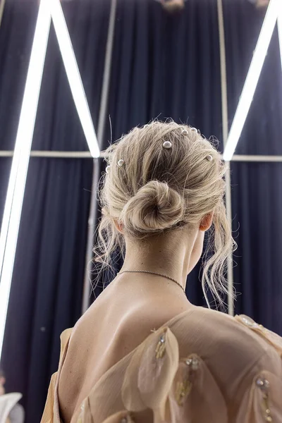 Menina loira fica contra espelho, visão traseira. fêmea com omoplatas nuas — Fotografia de Stock