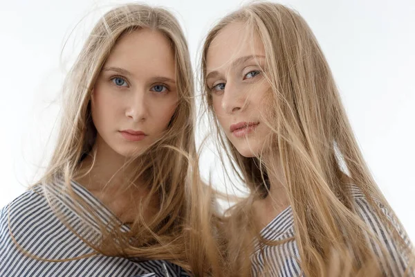 Two young teenage pretty caucasian twin sisters in striped shirts with long hair — Stock Photo, Image