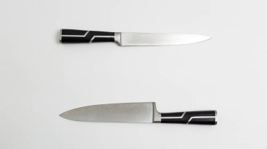 two sharp kitchen knives with black handles. white background flatlay. Top view