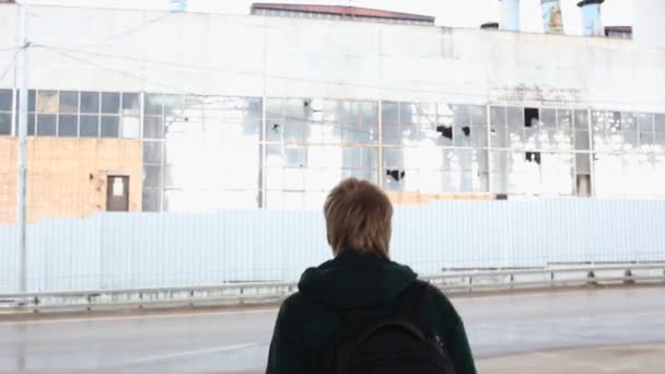 Achteraanzicht van de mens die loopt naar de ruïne van vervallen oude fabriek. ruïne — Stockvideo