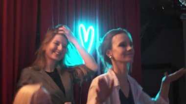 RUSSIA, VLADIMIR, 27 DEC 2019: Yeni yılda genç seksi kadınlar ve noel partisi sohbeti, dans, gülümseme, eğlenme, rahatlama. Gece kulübünde kırmızı perdeli karanlık dans pisti. Gençlik eğlencesi, gece hayatı.