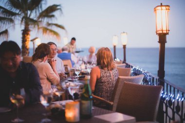 Deniz manzaralı bir sahil lokantası, açık hava restoranı masaları, akşam kumsalda akşam yemeği.