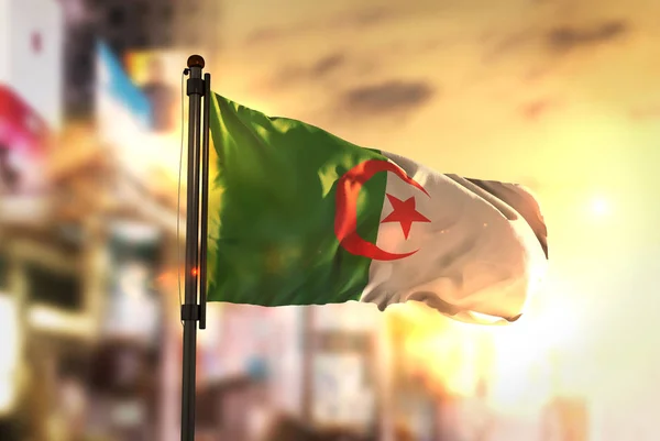 Флаг Алжира против размытого фона города на Санрайз Баклайт — стоковое фото