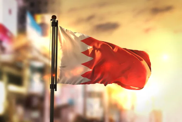 Bandeira do Bahrein contra o fundo borrado da cidade ao nascer do sol Backligh — Fotografia de Stock