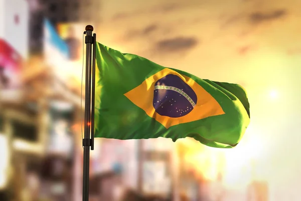 Brasilien flagga mot City suddig bakgrund på Sunrise bakgrundsbelysning — Stockfoto