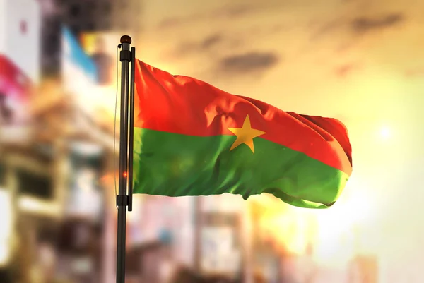 Burkina Faso vlag tegen stad wazig achtergrond bij zonsopgang Bac — Stockfoto