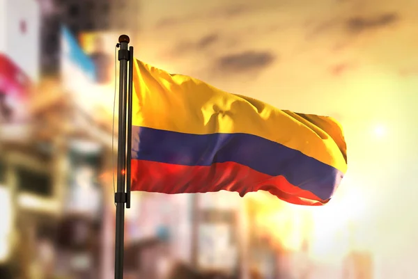 Colombia vlag tegen stad wazig achtergrond bij zonsopgang Backlig — Stockfoto