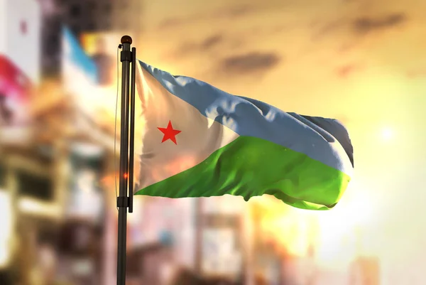 Djibouti Flag Against City Blurred Background At Sunrise Backlig — Stock Photo, Image