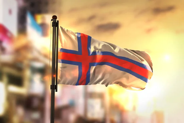 Faerské ostrovy vlajky proti City rozmazané pozadí v Sunrise Ba — Stock fotografie