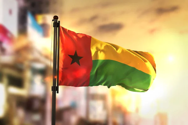 Guinea-Bissau Flag Against City Blurred Background At Sunrise Ba — Stock Photo, Image