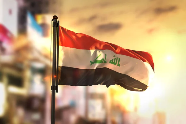 Прапор Іраку проти місто розмитим фоном при сходом сонця підсвічування — стокове фото