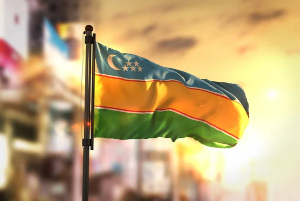 Республіка Каракалпакстан прапор проти міста розмитим фоном при сходом сонця B — стокове фото