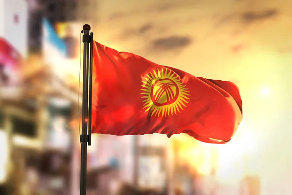 Kirguistán Bandera contra ciudad fondo borroso al amanecer Backl — Foto de Stock
