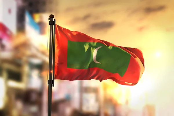 Flaga Malediwów przeciwko City niewyraźne tło na wschód Backlig — Zdjęcie stockowe