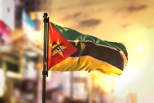Vlag van Mozambique tegen stad wazig achtergrond bij zonsopgang Backl — Stockfoto