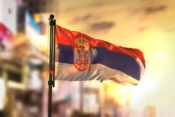 Bandera de Serbia contra ciudad borrosa fondo al amanecer retroiluminación — Foto de Stock
