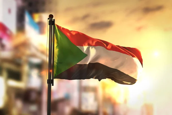 Szudán zászló City ellen elmosódott háttér: Sunrise háttérvilágítás — Stock Fotó