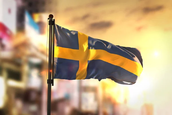 Флаг Швеции против размытого фона города на рассвете — стоковое фото