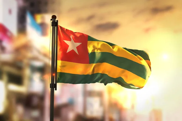 Togo Flag Against City Blurred Background At Sunrise Backlight — Stock Photo, Image