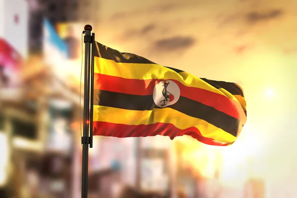 Uganda Flag Against City Blurred Background At Sunrise Backlight — Stock Photo, Image