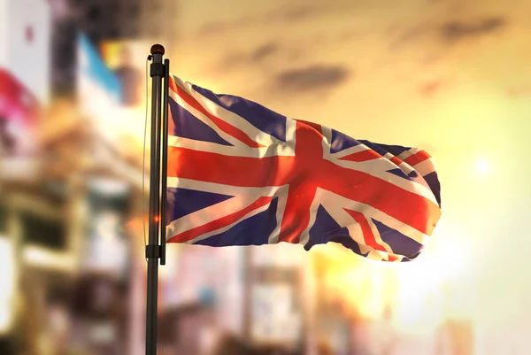 Vlag van het Verenigd Koninkrijk tegen stad wazig achtergrond bij Sunrise B — Stockfoto