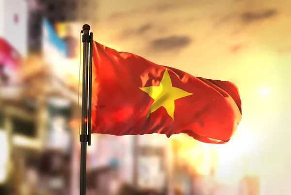 Vietnam vlag tegen stad wazig achtergrond bij zonsopgang Backligh — Stockfoto
