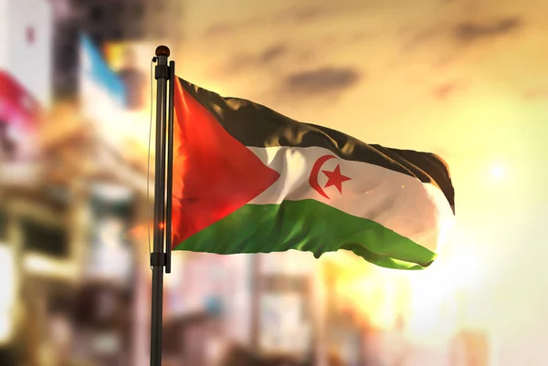 Västsahariska flaggan mot City suddig bakgrund på Sunrise Backligh — Stockfoto