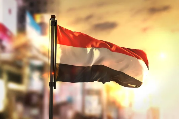 Vlag van Jemen tegen stad wazig achtergrond bij zonsopgang Backlight — Stockfoto