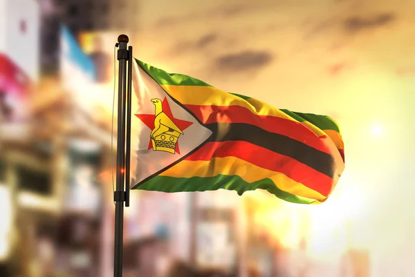Bandeira do Zimbábue Contra a Cidade Desfocada Ao Nascer do Sol Backlig — Fotografia de Stock