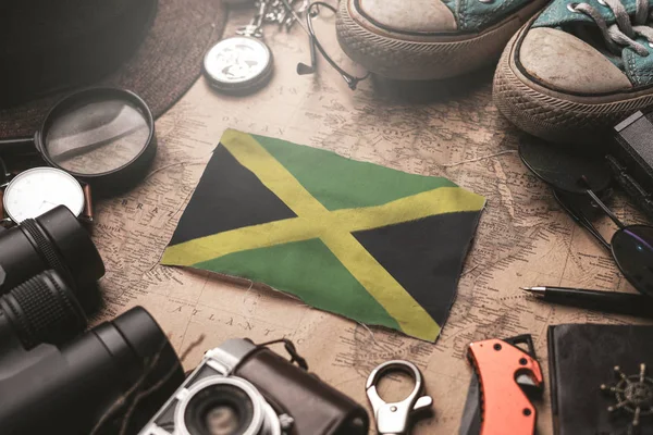 Bandiera giamaicana tra gli accessori del viaggiatore sulla vecchia mappa Vintage . — Foto Stock