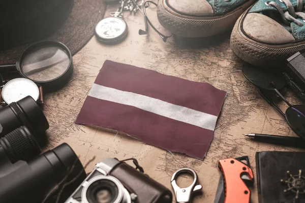 Lettonia Bandiera tra gli accessori del viaggiatore sulla vecchia mappa Vintage. T — Foto Stock