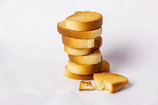 Beyaz ekmek krakerleri, üst üste istiflenmiş, kırıntılar etrafa saçılmış, beyaz arka plan. Sağlıklı yaşam için gevrek rusk ya da tost. Diyet yemek. Hint kahvaltısı ya da çayla atıştırmalık