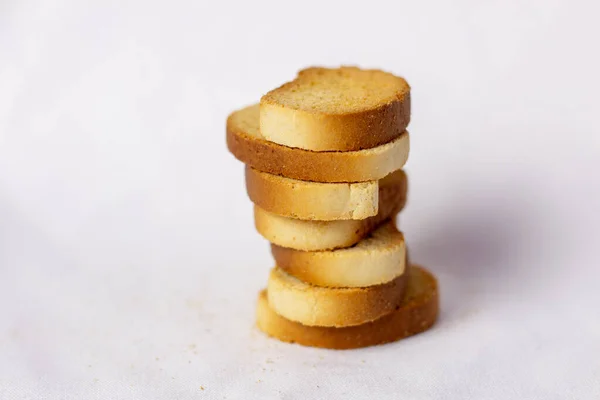 Beyaz ekmek krakerleri, üst üste istiflenmiş, kırıntılar etrafa saçılmış, beyaz arka plan. Sağlıklı yaşam için gevrek rusk ya da tost. Diyet yemek. Hint kahvaltısı ya da çayla atıştırmalık