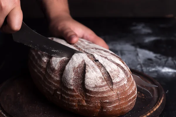 Primer plano de las manos del panadero cortando pan fresco del horno —  Fotos de Stock