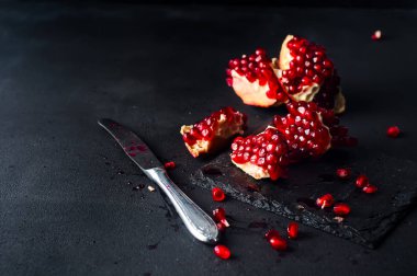 Nar ve nar taneleri karanlık bir arka plan üzerinde