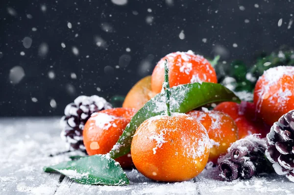 Složení s mandarinkami zelené listy, sníh a šiška — Stock fotografie