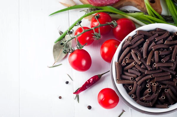Macarrão italiano seco espiralina, tomates cereja vermelhos, salsicha, ainda vida — Fotografia de Stock
