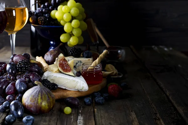 Uva, queso, higos y miel con una copa de vino blanco —  Fotos de Stock