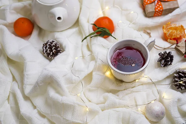 Hot Cup of tea with tangerines and sweaters on bed — Stock Photo, Image