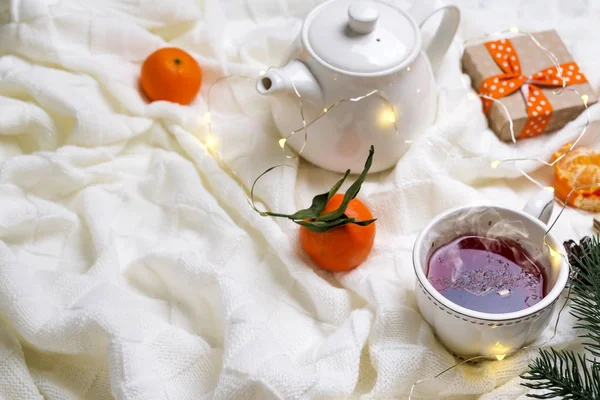 Hot Cup of tea with tangerines and sweaters on bed — Stock Photo, Image