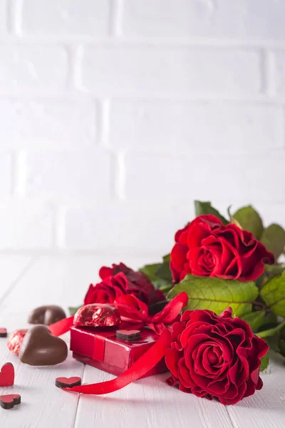 Čerstvé červené růže a krabičky na dřevěný stůl — Stock fotografie